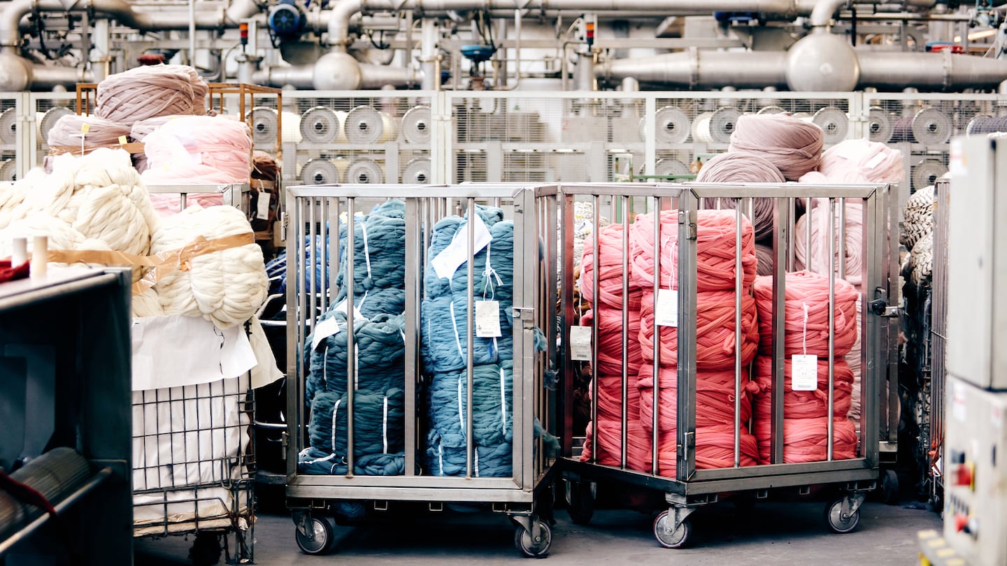 Trolleys full of blue and red yarn sit on a factory floor.
