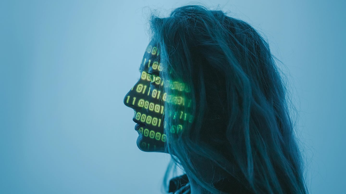 A woman in profile with binary code projected on her face.